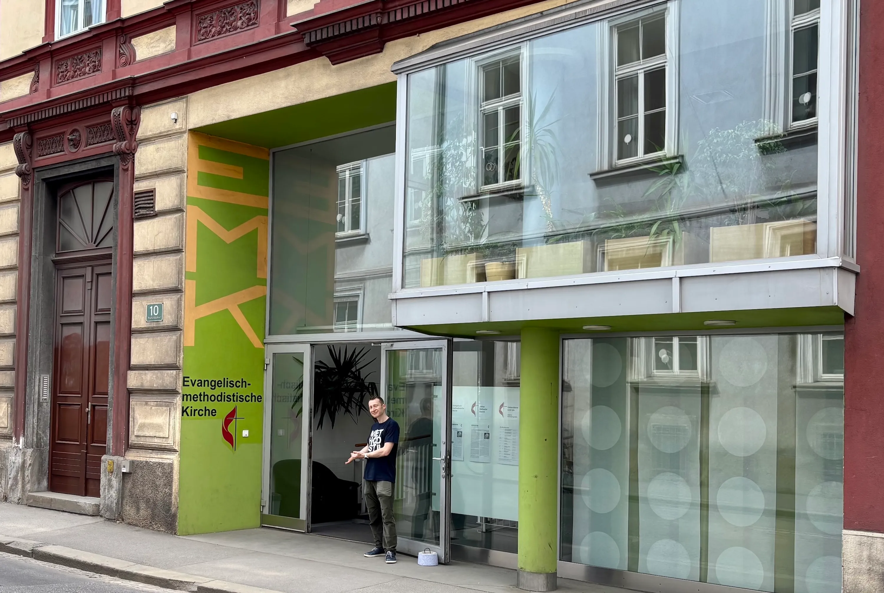 Eike Nungesser steht in Einladender Haltung vor dem Eingang der EmK Graz