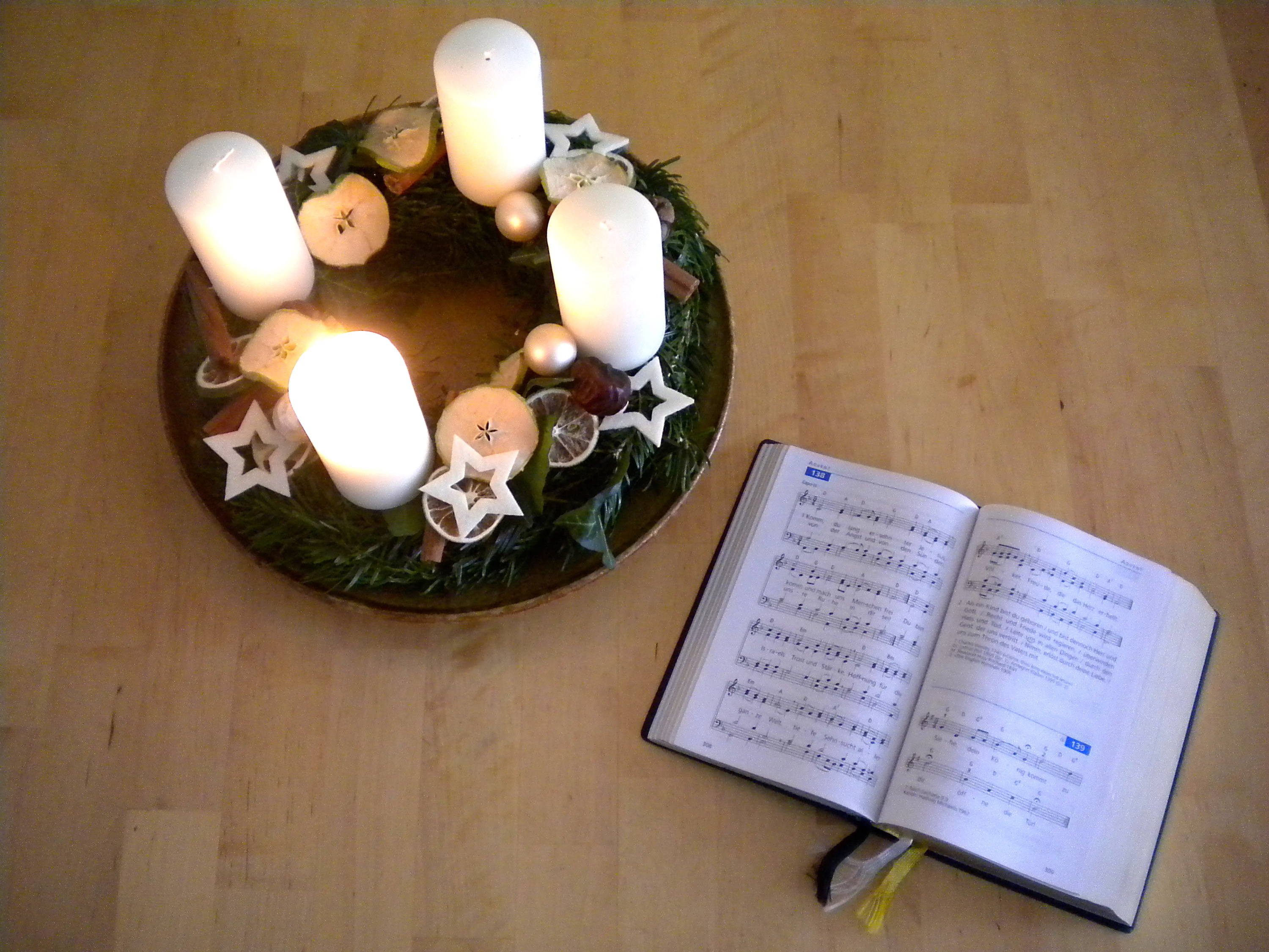Anregungen für den Advent Adventkranz mit entzündeter 1. Kerze und Gesangbuch EM aufgeschlagen bei Lied 138 "Komm, du lang ersehnter Jesus"