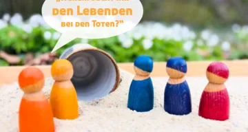 Bunte Holzfiguren auf Sand vor dem leeren Grab. Die leuchtenden Figureb fragen: "Warum sucht ihr den Lebenden bei den Toten?" (Lukas 24,5)